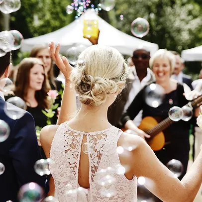 Mariage extérieur avec mariée de dos, bulles, invités souriants et musicienne à la guitare à Autrèche près de Tours et d'Amboise en Indre-et-Loire 37