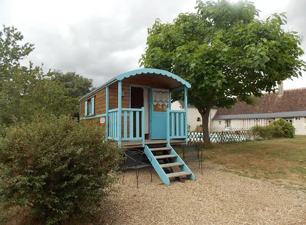 Roulotte bleue et bois au premier plan, avec un grand arbre et une maison en arrière-plan à Autrèche près de Tours et d'Amboise en Indre-et-Loire 37