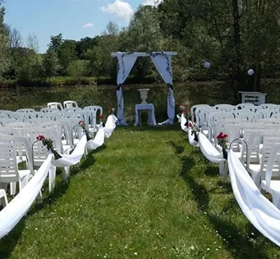 Allée de mariage extérieure avec chaises blanches, arc drapé, au bord d'une étendue d'eau à Autrèche près de Tours et d'Amboise en Indre-et-Loire 37