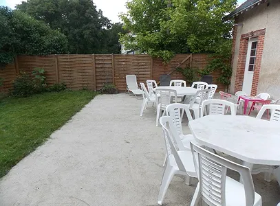 Terrasse extérieure avec tables et chaises blanches, pelouse, et clôture en bois à Autrèche près de Tours et d'Ambois en Indre-et-Loire 37