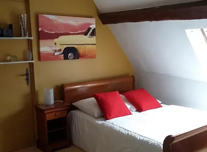 Chambre mansardée avec lit double, coussins rouges, table de chevet et tableau de voiture jaune à Autrèche près de Tours et d'Ambois en Indre-et-Loire 37