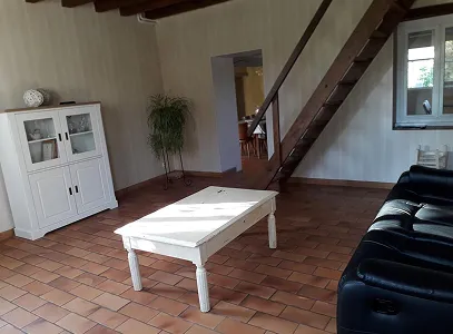 Séjour rustique avec escalier en bois, sol carrelé, canapé noir et buffet blanc à Autrèche près de Tours et d'Ambois en Indre-et-Loire 37