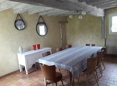 Salle à manger rustique avec longue table en bois, chaises, poutres apparentes et murs jaunes à Autrèche près de Tours et d'Ambois en Indre-et-Loire 37