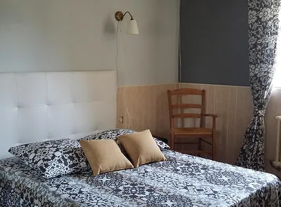Chambre à coucher avec un lit, une tête de lit blanche, des coussins beiges et une chaise en bois à Autrèche près de Tours et d'Ambois en Indre-et-Loire 37