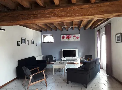 Salon confortable avec poutres apparentes, canapés sombres, TV et décoration murale florale à Autrèche près de Tours et d'Ambois en Indre-et-Loire 37