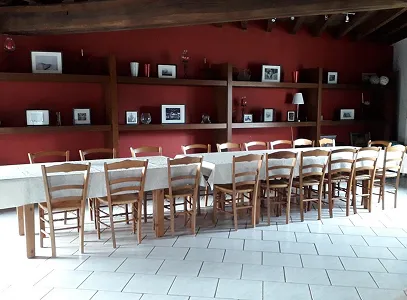 Longue table de salle à manger avec chaises en bois devant un mur rouge avec étagères à Autrèche près de Tours et d'Ambois en Indre-et-Loire 37